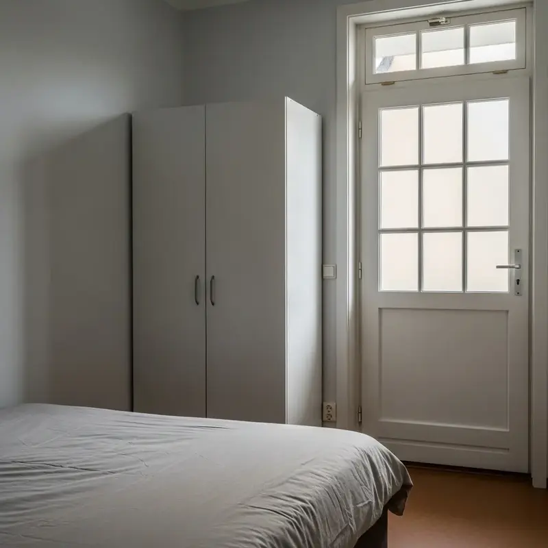 Quarto individual mobiliado com cama, escrivaninha e janela, bem iluminado.